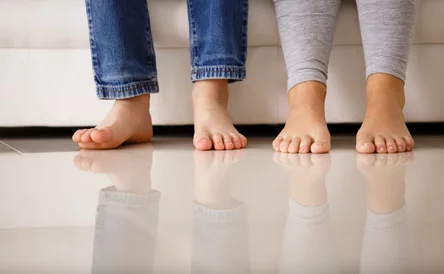 Barefoot family sitting on sofa, low section