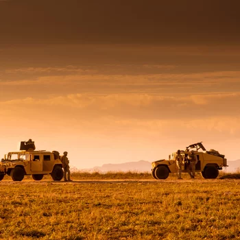 Soldiers marines patrolling on foot and escorted by a Humvee