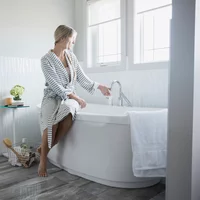 Woman in bathrobe preparing a bath in bathroom