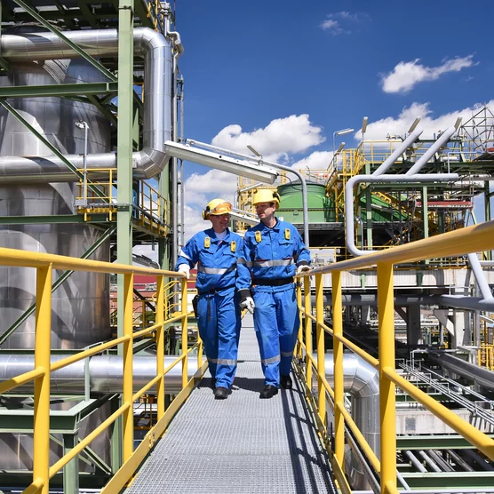 chemical industry plant - workers in work clothes in a refinery with pipes and machinery